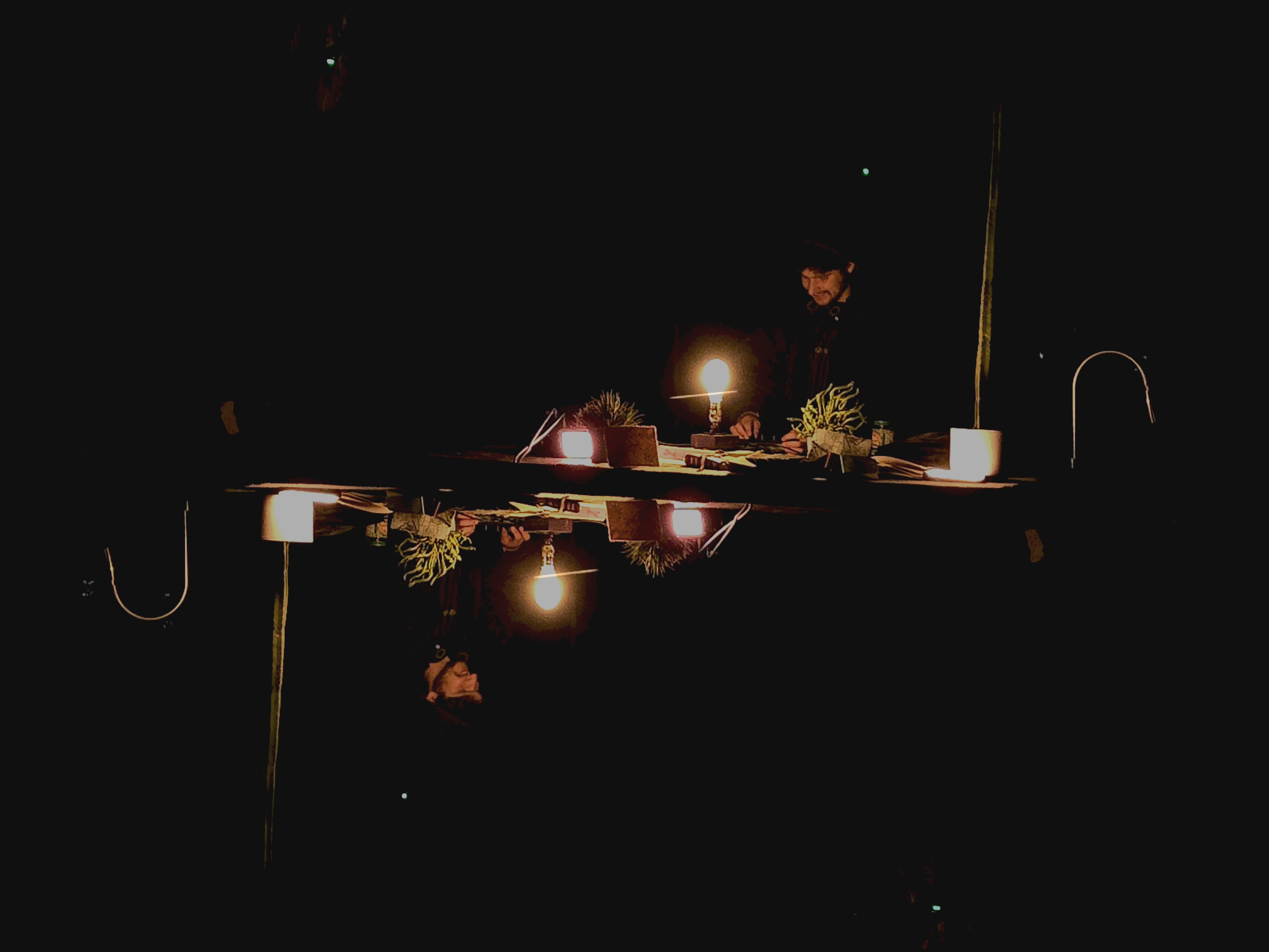 The artist performing behind a reflective surface in a dark room